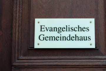Schild mit Aufschrift Evangelisches Gemeindehaus an Holzt&uuml;r