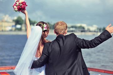 Happy bride and groom hugging on a yacht at beautiful and wonderful sunny summer day in...