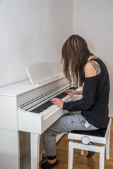 Junge langhaarige Frau spielt daheim Digital Piano