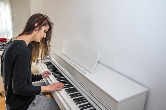 Junge Frau spielt daheim digitales Klavier