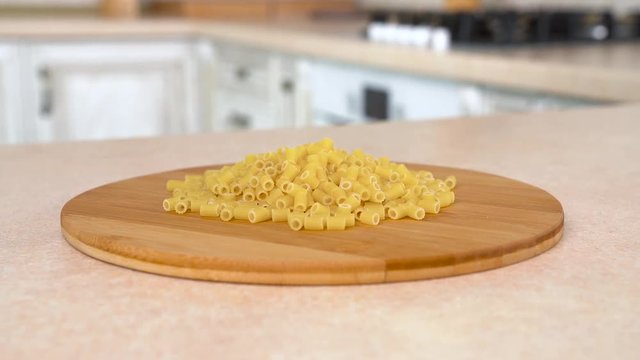 Heap of ditali tubetti rigati pasta on the plate. Rotating camera with white kitchen on the background. Dolly-shot.