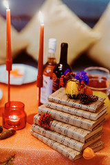 Autumn wedding decoration with flower composition with roses, chrysanthemum, maple leaves, pumpkin, books and candles. Haloween concept