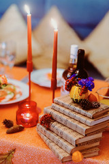 Autumn wedding decoration with flower composition with roses, chrysanthemum, maple leaves, pumpkin, books and candles. Haloween concept