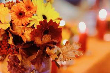 Autumn wedding decoration with flower composition with roses, chrysanthemum, maple leaves, pumpkin, books and candles. Haloween concept