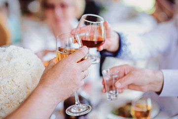 Alcohol cheers clinking glasses of champagne in hands on bright lights background. Party concept