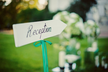 Emerald green wedding decoration on reception zone before wedding ceremony. Sunny day wedding in forest or green park. Summer event concept photo with selective focus close up
