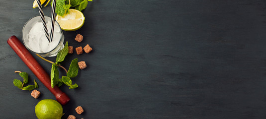 Preparation of Mojito cocktail. Bar utensils and ingredients mint, lime, ice and cane sugar. Top view with copy space