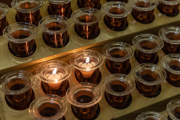 Two Lit Prayer Candles in a Candle Rack in Church