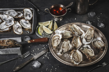 Plate of open oysters on ice with vinegar souce and lemon