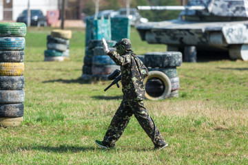 two teams of paintball players in camouflage form with masks, helmets, guns on the field in the summer. sport life concept