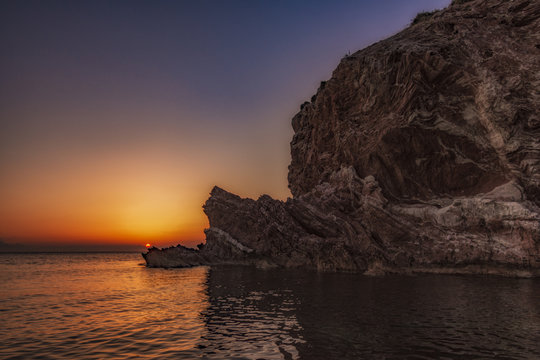 Sole che tramonta dietro la scogliera di Cala Rossa, Terrasini - provincia di Palermo IT	