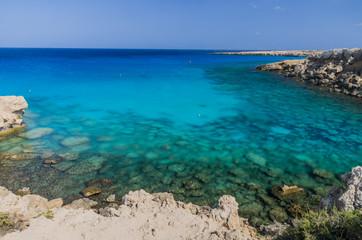 Fototapeta na wymiar Cape Grecco beautiful crystal clear beach with a tourist cruis approaching, Ayia Napa,Cyprus