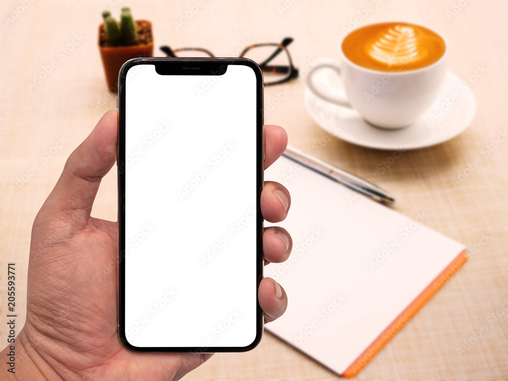 Poster hand using smartphone white screen with workspace on wood table.