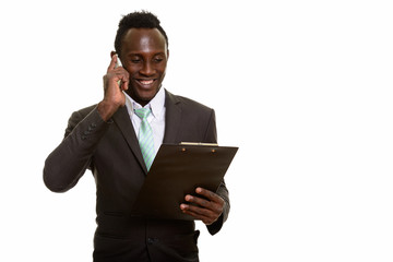 Young happy black African businessman smiling while talking on m