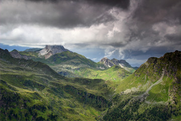 Carnic Alps Main Ridge in bad weather conditions with grassy rocky slopes and Kinigat Cavallino peak covered by low dark clouds, Karnischer Hohenweg Osttirol Austria / Veneto Belluno Italy Europe