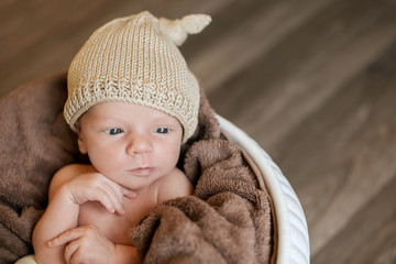 A little child in a beige cap lies in the basket