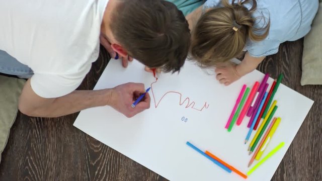 Top view of father and little daughter drawing picture with colorful felt tip pencils
