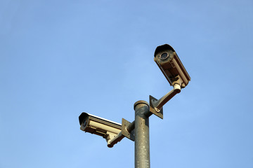 Fototapeta premium Two closed circuit camera installation in one post on blue sky background. A closed-circuit television camera (CCTV camera) can produce images or recordings for surveillance or other private purposes.