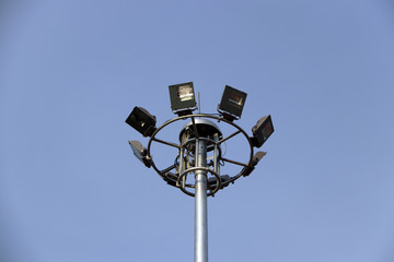 Many street lamp surround installation in one post on blue sky background. It use for the road or sports arena stadium.