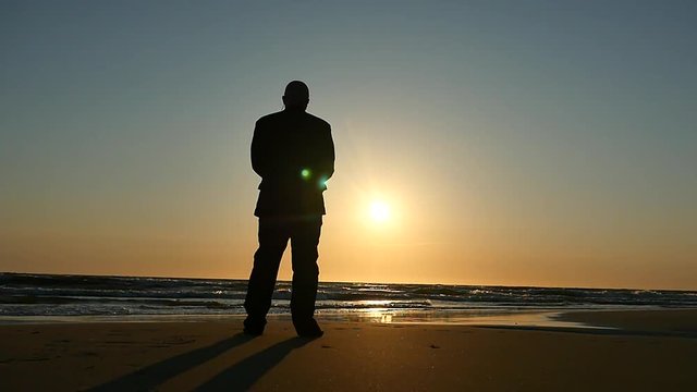 standing man watching sunset beach panoramic shot silhouette