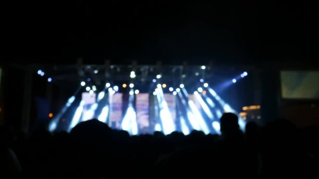 Crowd at concert  and blurred stage lights of people dancing at the rock 'n roll concert.