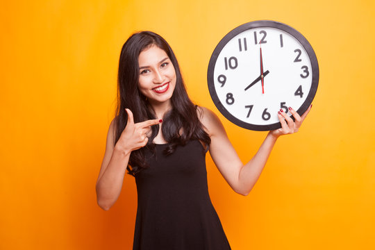 Young Asian woman thumbs up with a clock.