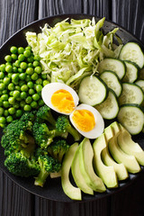 Color green diet: delicious fresh avocado, peas, cabbage, cucumber, eggs and broccoli close-up. Vertical top view