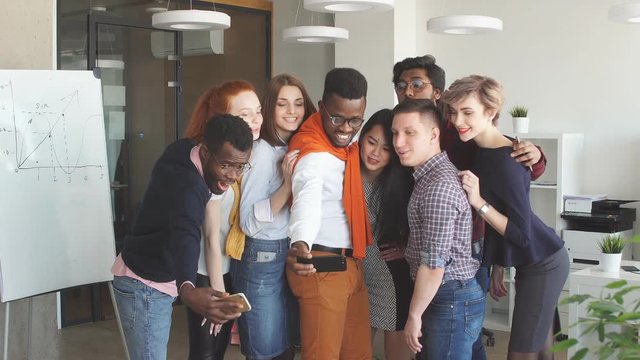 African guy taking picture with his multiracial friends in the modern studio.