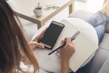 Young woman using smartphone at cozy home on sofa in living room