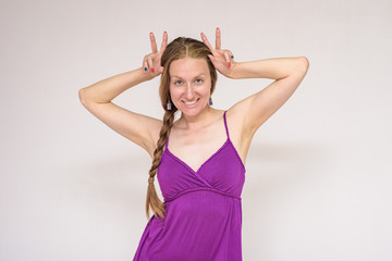 Portrait of a beautiful woman on a white background showing horns