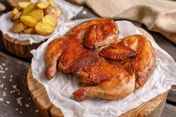 Chicken tobacco and potato garnish on wooden spilah. Close-up.