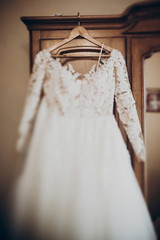 luxury wedding dress on hanger at wooden closet in rustic room. space for text. wedding morning preparation,getting ready. stylish gown
