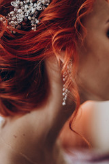 stylish bride detail, luxury earring jewelry and red hair curl, beautiful wedding dress. rustic wedding morning preparation. bridal getting ready. emotional moment. space for text