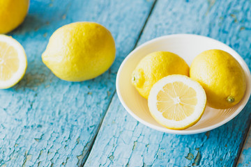 Yellow lemons in the white plate, wooden background