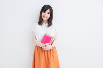 Fototapeta premium 白壁に手帳を持って立つ女の子
