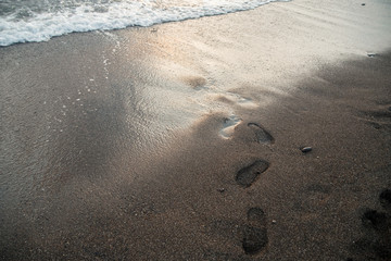 Footprints in the sand at sunset sun