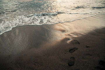 Footprints in the sand at sunset sun