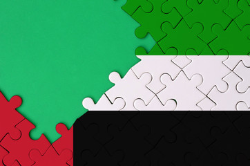United Arab Emirates flag  is depicted on a completed jigsaw puzzle with free green copy space on...