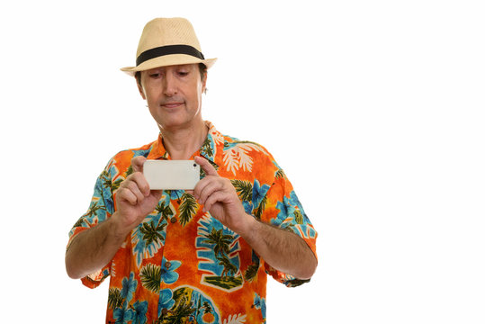 Studio shot of mature man taking picture with mobile phone