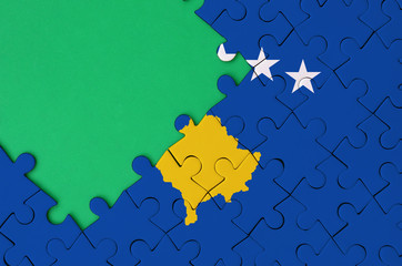 Kosovo flag  is depicted on a completed jigsaw puzzle with free green copy space on the left side