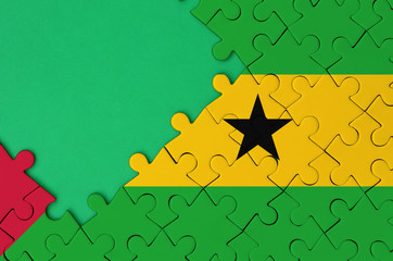 Sao Tome and Principe flag  is depicted on a completed jigsaw puzzle with free green copy space on...