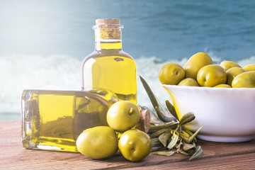bowl of olives and bottle of extra virgin oil on background