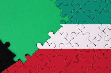 Kuwait flag  is depicted on a completed jigsaw puzzle with free green copy space on the left side