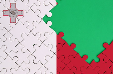 Malta flag  is depicted on a completed jigsaw puzzle with free green copy space on the right side