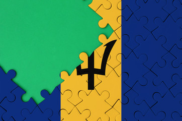 Barbados flag  is depicted on a completed jigsaw puzzle with free green copy space on the left side