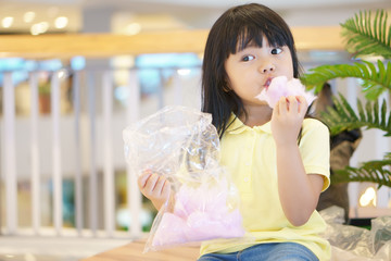 asian children cute or kid girl smile and fun with enjoy eating pink candy floss or cotton candy...