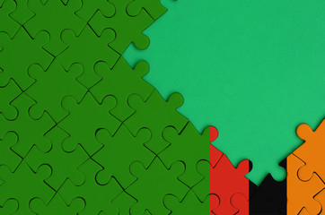 Zambia flag  is depicted on a completed jigsaw puzzle with free green copy space on the right side