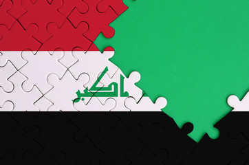 Iraq flag  is depicted on a completed jigsaw puzzle with free green copy space on the right side