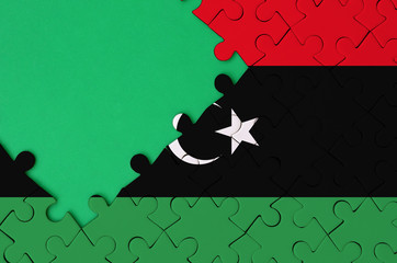 Libya flag  is depicted on a completed jigsaw puzzle with free green copy space on the left side