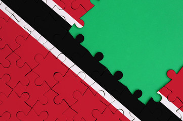 Trinidad and Tobago flag  is depicted on a completed jigsaw puzzle with free green copy space on...